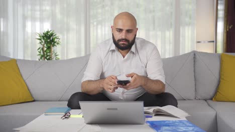 Home-office-worker-man-gets-frustrated-while-looking-at-phone.